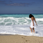 Ragazza che cammina in spiaggia bagnandosi i piedi nel mare